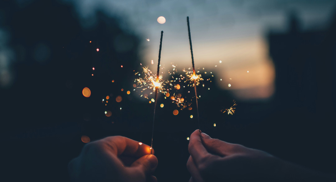 Dos personas sostienen bengalas encendidas en una celebración nocturna