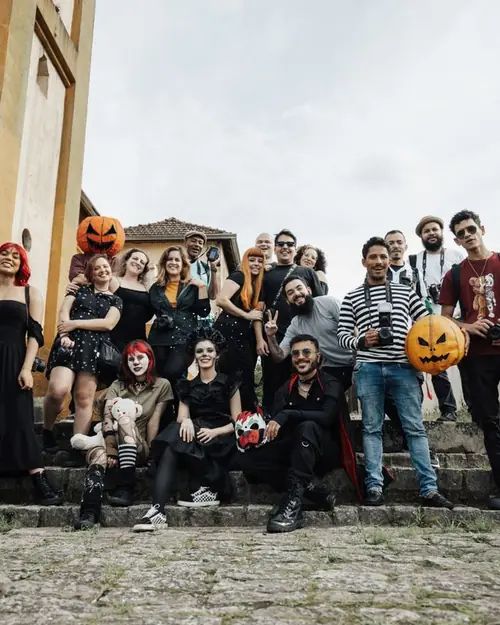 Große Gruppe von Freunden in Halloween-Kostümen auf Steinstufen mit Kürbislaternen Große Gruppe von Freunden in Halloween-Kostümen auf Steinstufen mit Kürbislaternen